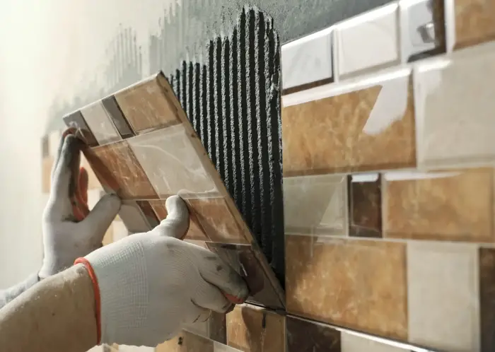 Artisan Carreleur Bruges en train de remplacer un carreau mural avec précision.