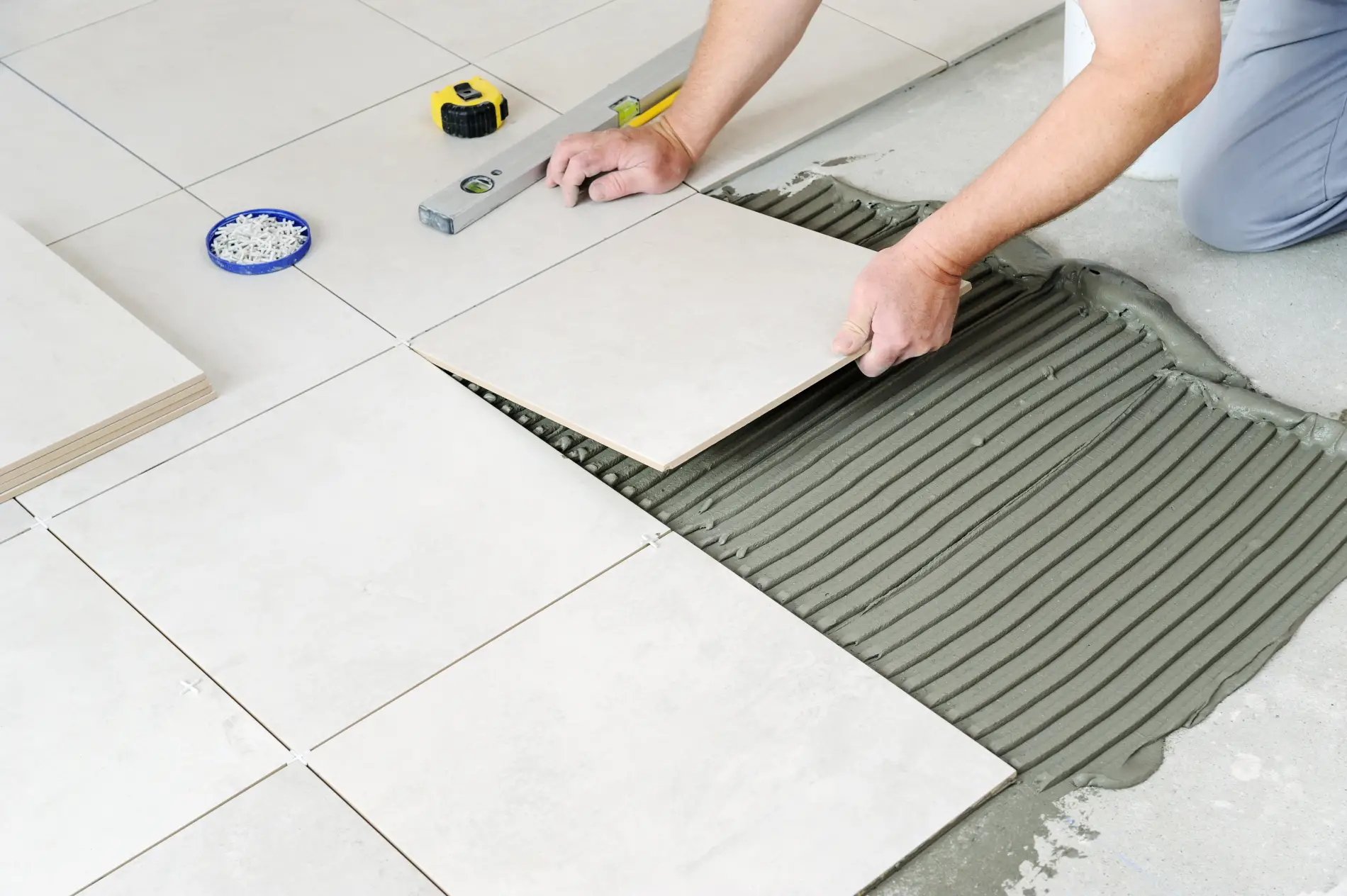 Pose méticuleuse de carrelage au sol, couverte par la garantie décennale
